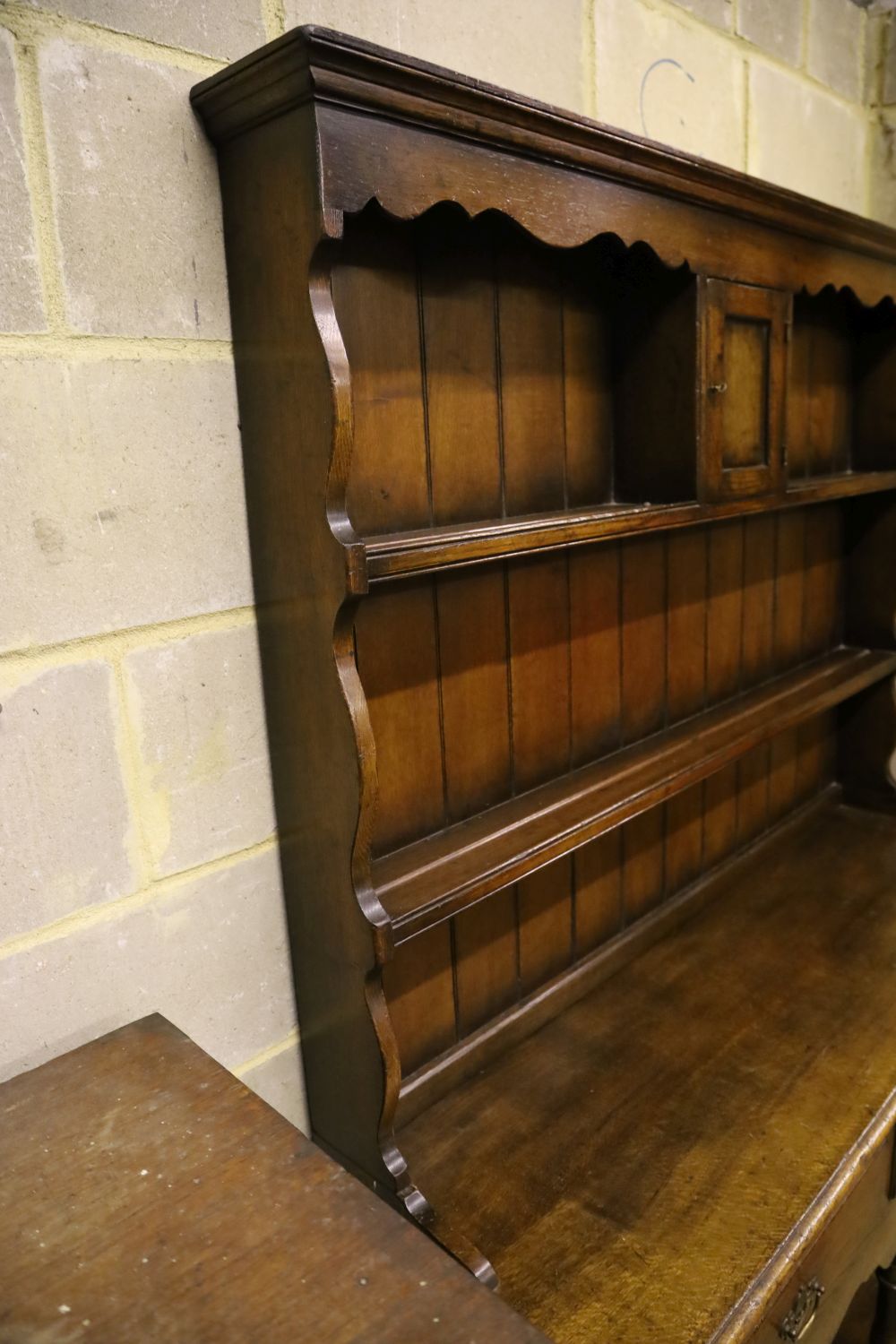 A small Georgian style reproduction oak dresser, having shelved boarded back, shaped apron and pot shelf, width 137cm, depth 44cm, heig